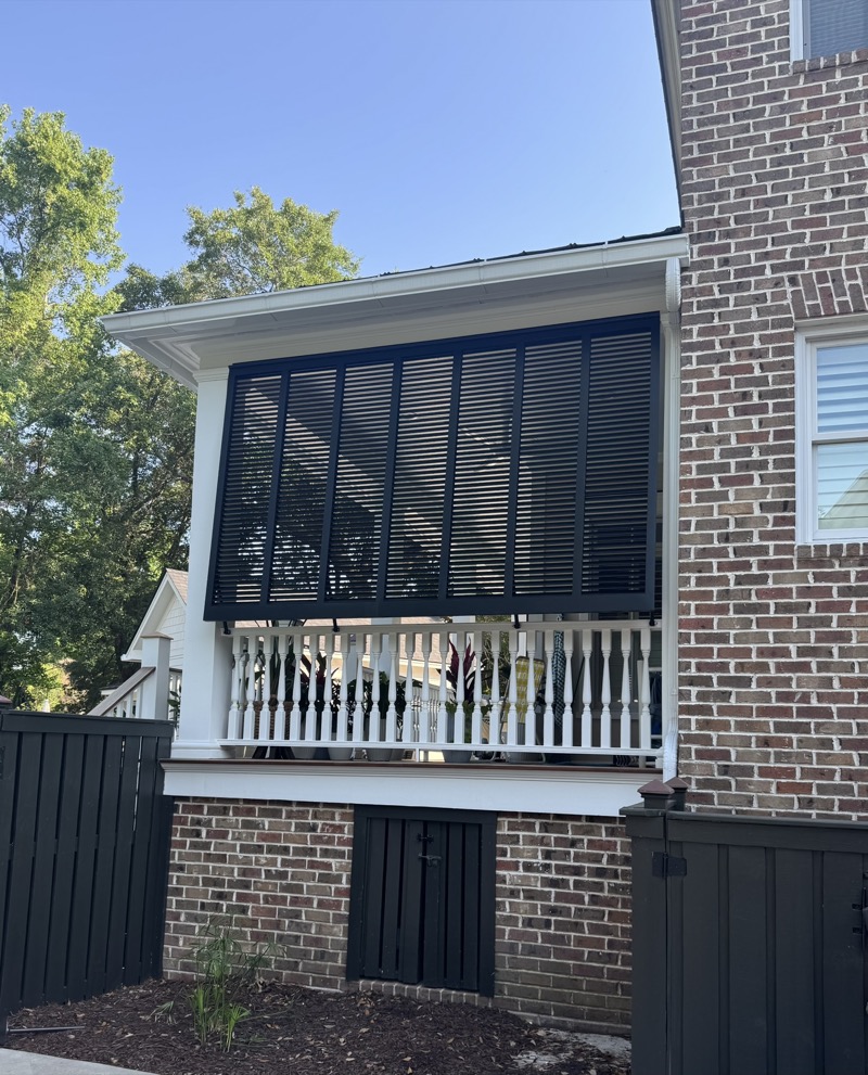 Charcoal Bahama shutters adding curb appeal to a classic brick Charleston home