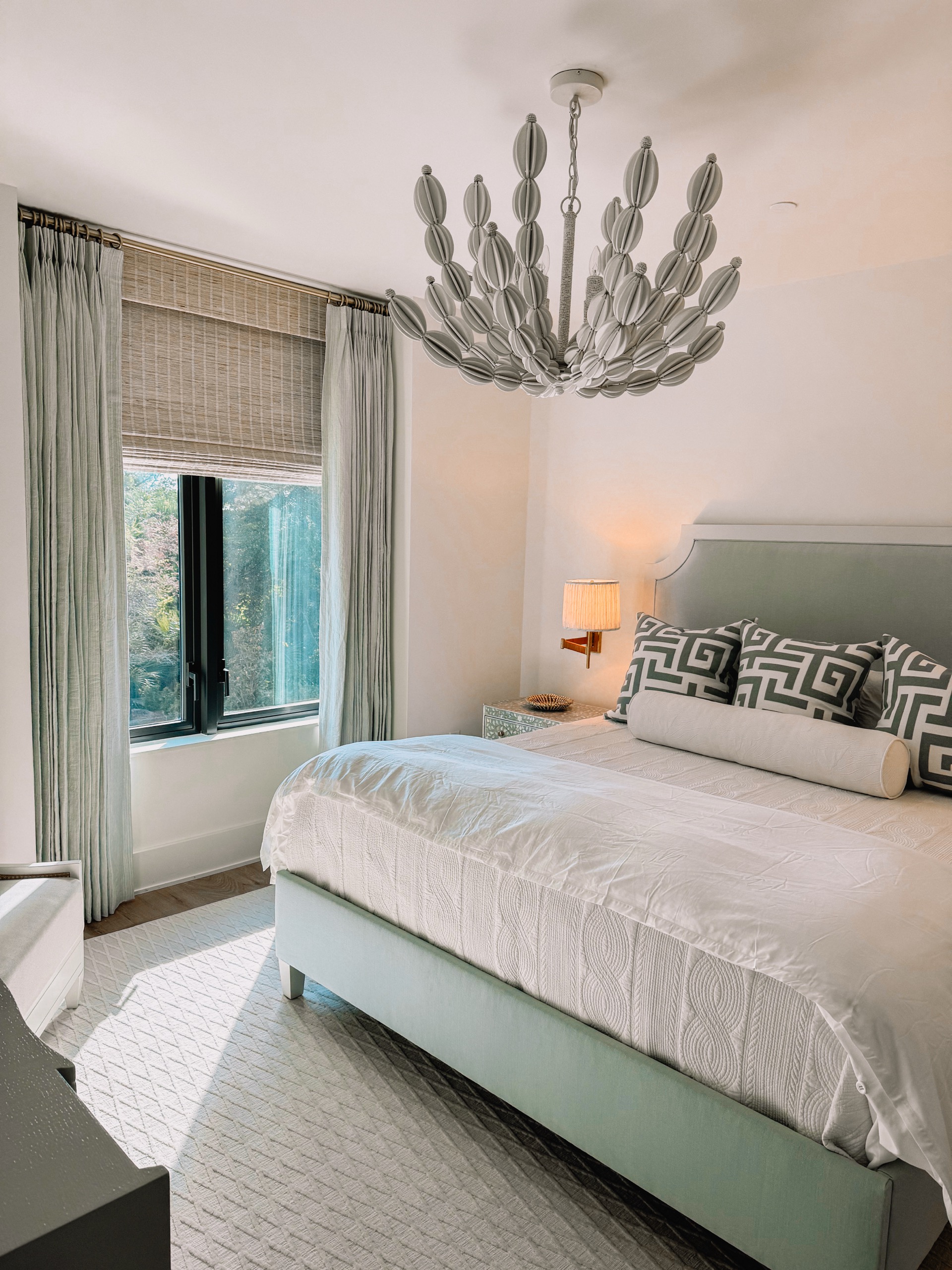 Elegant bedroom with custom drapery and woven wood shades by Charleston Custom Shutters
