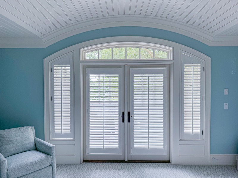 Custom plantation shutters on French doors with arched transom in Charleston bedroom